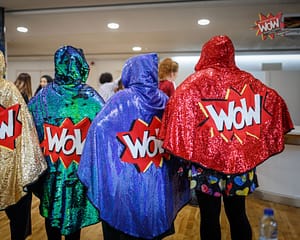 Four sparkly WoW capes being modelled here by four volunteers.